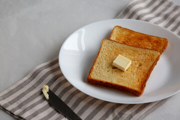 Homemade Toasted Bread Slice with Butter on a Plate, side view.