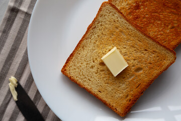 Homemade Toasted Bread Slice with Butter on a Plate, top view.
