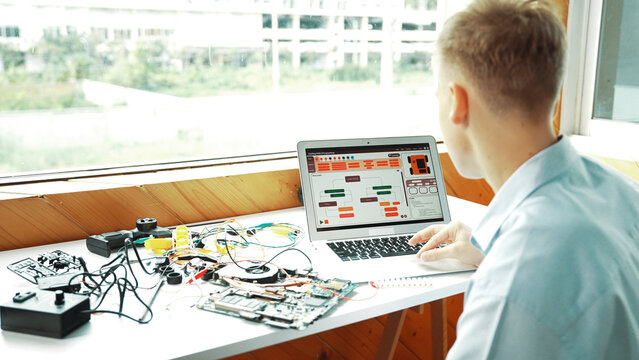 Caucasian student looking at laptop screen while coding engineering prompt or programing system. Back view of smart teenager working by using computer and electronic tool at STEM class. Edification.