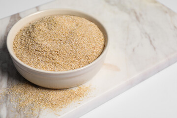 Oat bran in bowl on white table, closeup