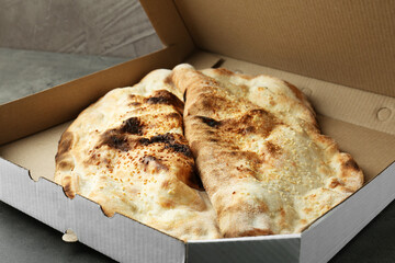 Delicious calzones in cardboard box on grey table, closeup