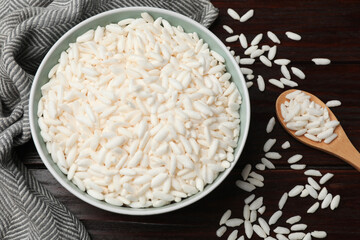 Puffed rice in bowl and spoon on wooden table, flat lay