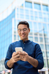Happy professional businessman holding smartphone in hands looking at cellphone outdoor, young...