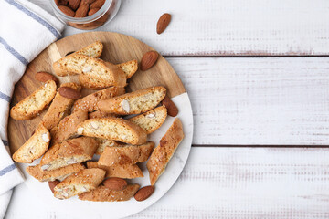 Tasty almond biscuits (Cantuccini) and nuts on light wooden table, flat lay. Space for text