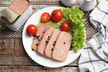 Tasty canned meat, tomatoes, lettuce and spices on wooden table, top view