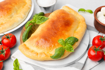 Tasty vegetarian calzones with basil, tomatoes and mozzarella cheese on table, closeup