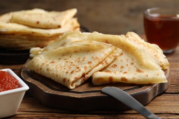 Tasty crepes and red caviar on wooden table, closeup