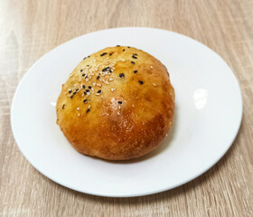Delicious freshly baked bread roll with sesame seeds on a plate