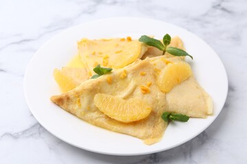Plate with tasty crepes Suzette on white marble table, closeup