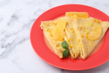 Plate with tasty crepes Suzette on white marble table, closeup. Space for text
