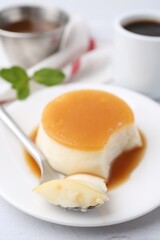 Tasty pudding with caramel sauce served on white textured table, closeup