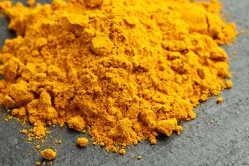 Heap of turmeric powder on grey table, closeup