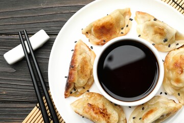 Delicious fried gyoza dumplings with sesame seeds served on wooden table, top view