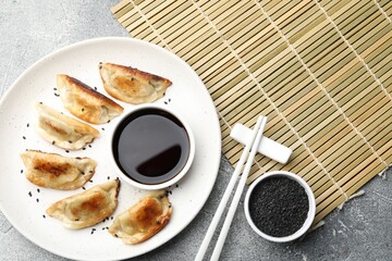 Delicious fried gyoza dumplings with sesame seeds served on grey table, flat lay