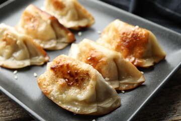 Fried gyoza dumplings with sesame seeds on wooden table, closeup