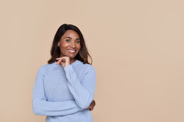 Smiling young adult African American woman, happy lady customer in casual wear isolated on beige background looking at camera advertising product or service with copy space for ads aside. Portrait.