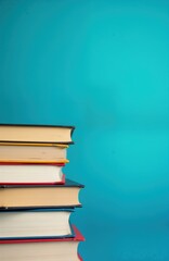 Fototapeta premium Stacked colorful books on blue background. Education concept for college library. Books represent knowledge, learning. Study area in university campus. Perfect for advertising educational promotions.