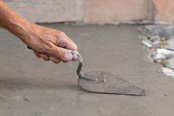 Cementation of a garden path.A man manually spreads the cement mixture with a trowel.Spring work in the garden.
