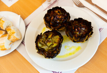 Delicious dish of Mediterranean cuisine is appetizing artichokes on a plate, sprinkled with salt on top