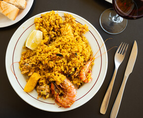 Fresh cooked seafood paella garnished with large king prawns. Gastro tourism, acquaintance with culinary traditions of countries, gourmet restaurant