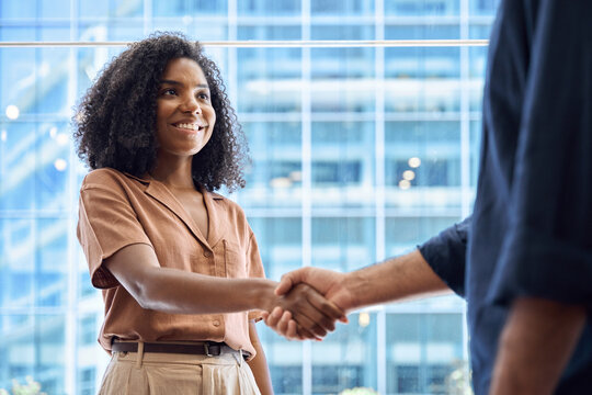 Handshake of happy African business woman and business man meeting in office. Young female bank manager greeting male client partner as concept of cooperation success, financial partnership agreement.