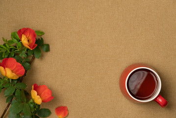 Rosehip flowers with cup of tea on fabric background. Flat lay, top view. Copy space