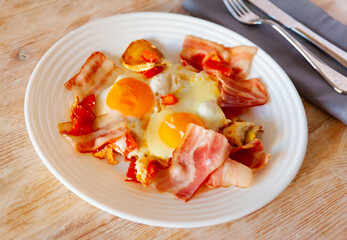 Bacon with fried potato and egg served on plate on wooden table