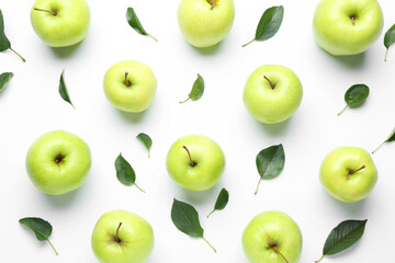 Green apples and leaves on white background, flat lay