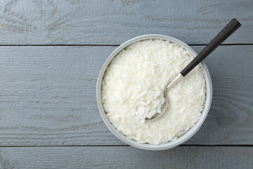 Soy wax in bowl on grey wooden table, top view. Space for text