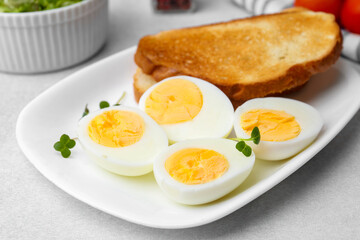 Hard boiled eggs with bread on light table, closeup