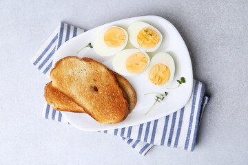 Hard boiled eggs with bread on light table, top view