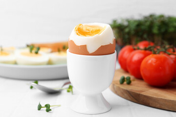 Soft boiled egg on white tiled table, closeup
