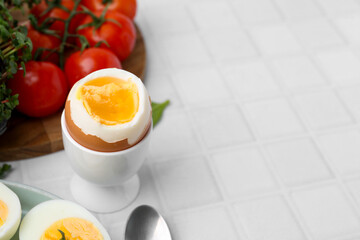 Soft boiled egg on white tiled table, closeup. Space for text