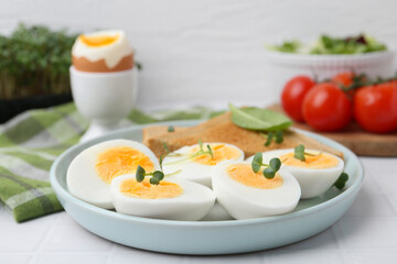 Cut hard boiled eggs with bread on white tiled table, closeup