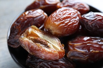 Many tasty dried dates in bowl on table, closeup