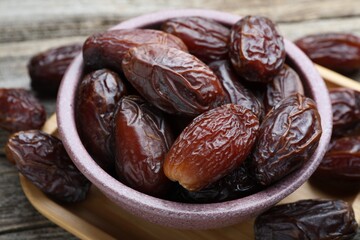 Many tasty dried dates in bowl on table, closeup