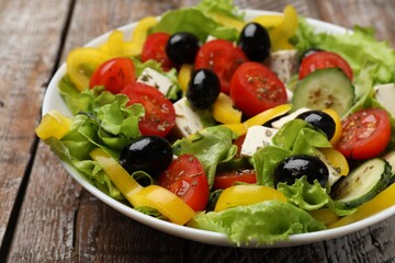 Delicious fresh Greek salad on wooden table, closeup
