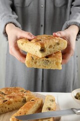 Woman with pieces of delicious focaccia bread at table, closeup