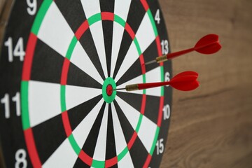 Dart board and red arrows on wooden background, closeup