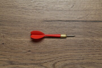 One red dart arrow on wooden table, top view