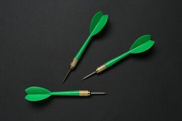 Green dart arrows on black background, flat lay