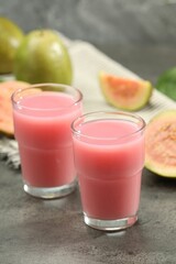 Refreshing guava juice and fresh fruits on grey table, closeup