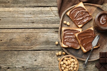 Tasty sandwiches with chocolate butter and hazelnuts on wooden table, flat lay. Space for text