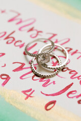 Elegant wedding rings displayed on a colorful invitation design with calligraphy details