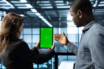 Team of engineers working in server farm, using chroma key tablet to analyze data. Employees working together in data center using isolated screen device, ensuring system integrity and security