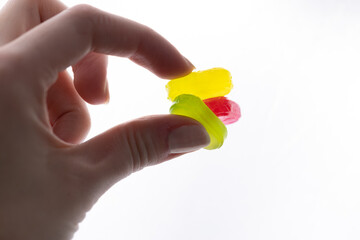 on white background in women's fingers caramel candies green pink yellow a lot of sugar development of diabetes and caresses sweets for children