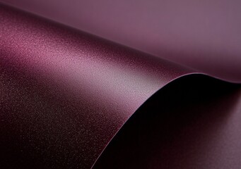 Curving gracefully, a sheet of shimmering purple metallic paper forms an abstract composition, highlighting a captivating interplay of light and shadow across its smooth surface
