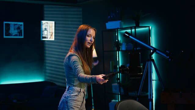 Girl holding selfie smartphone camera, filming herself doing room tour to viewers watching her online content. Teenager doing video presenting her home to social media channels fans, camera B