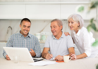 Fototapeta premium Couple of elderly man and woman while discussing deal with smiling male salesman in kitchen
