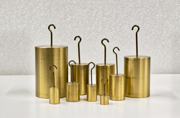 Brass hooked weights scientific laboratory measuring equipment on table.